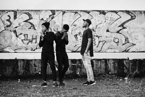 black and white image of young people standing in front of urban graffiti